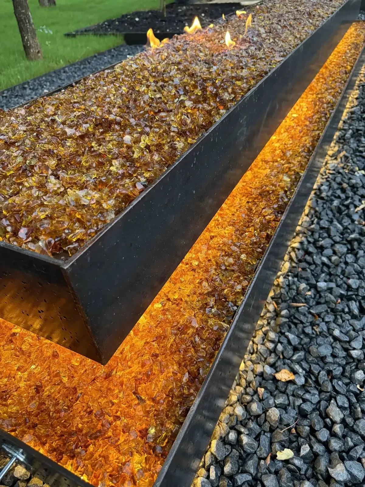 Floating limestone boulder fire pit with propane flame on a Lakeway marbled concrete patio