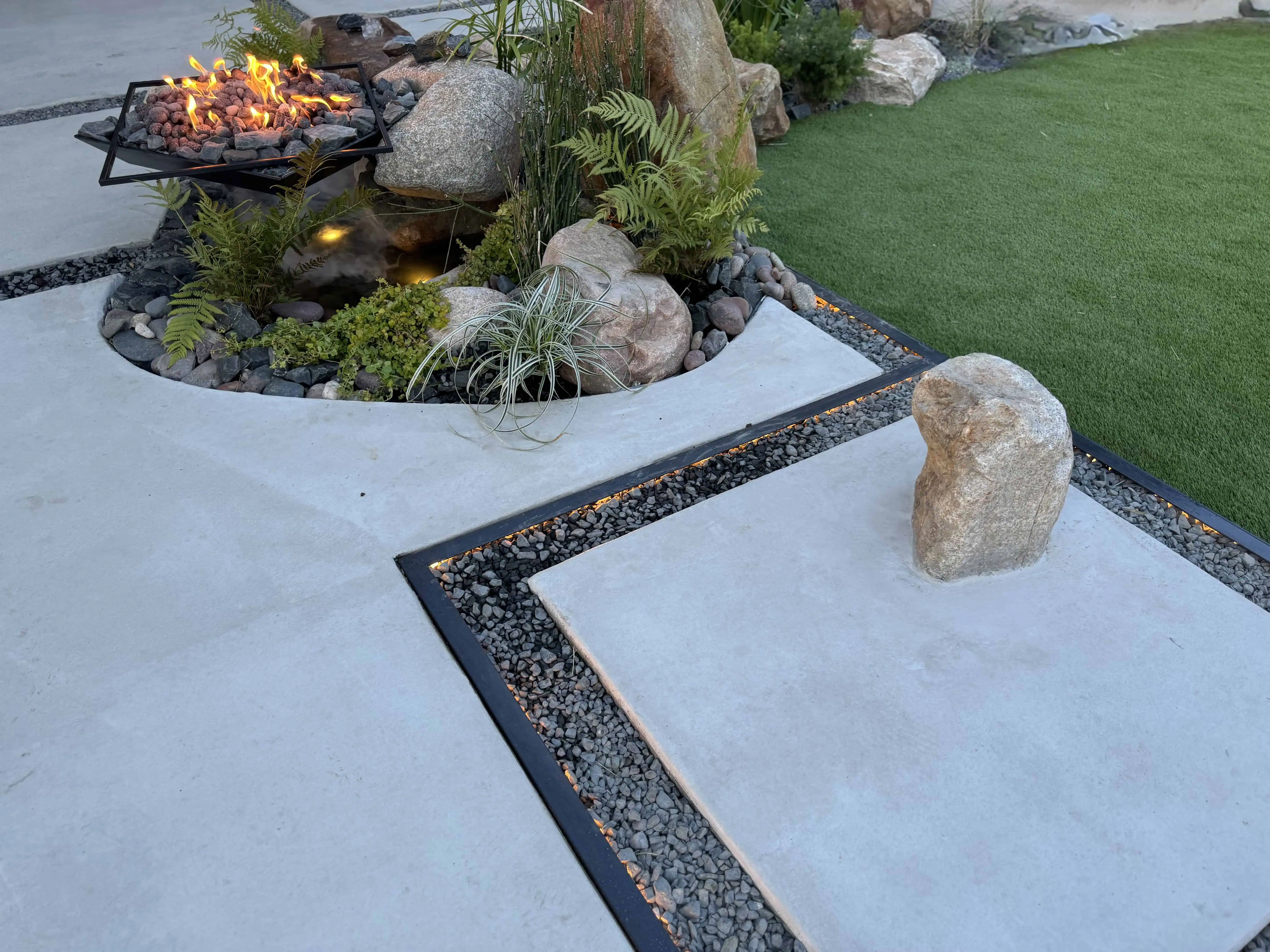 COB-lit paver joints with boulder fountain and fire pit in planting bed — Pflugerville TX