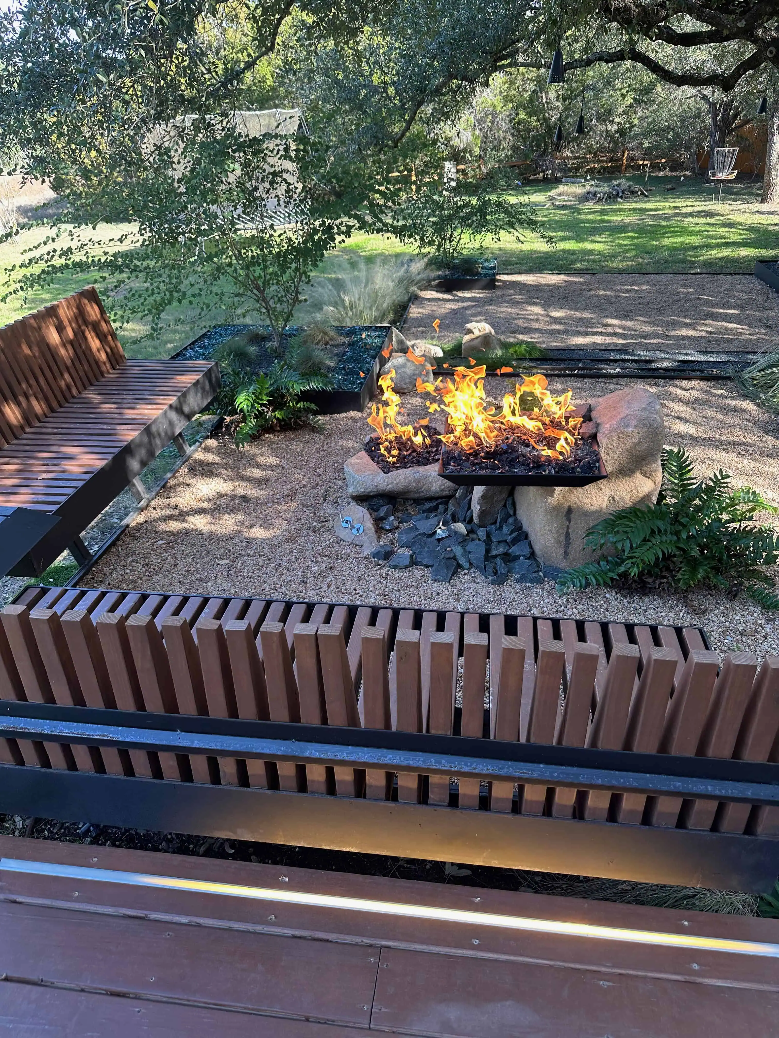 Terraced deck view with stone fire pit and cantilevered planter foreground — Circle C Austin TX