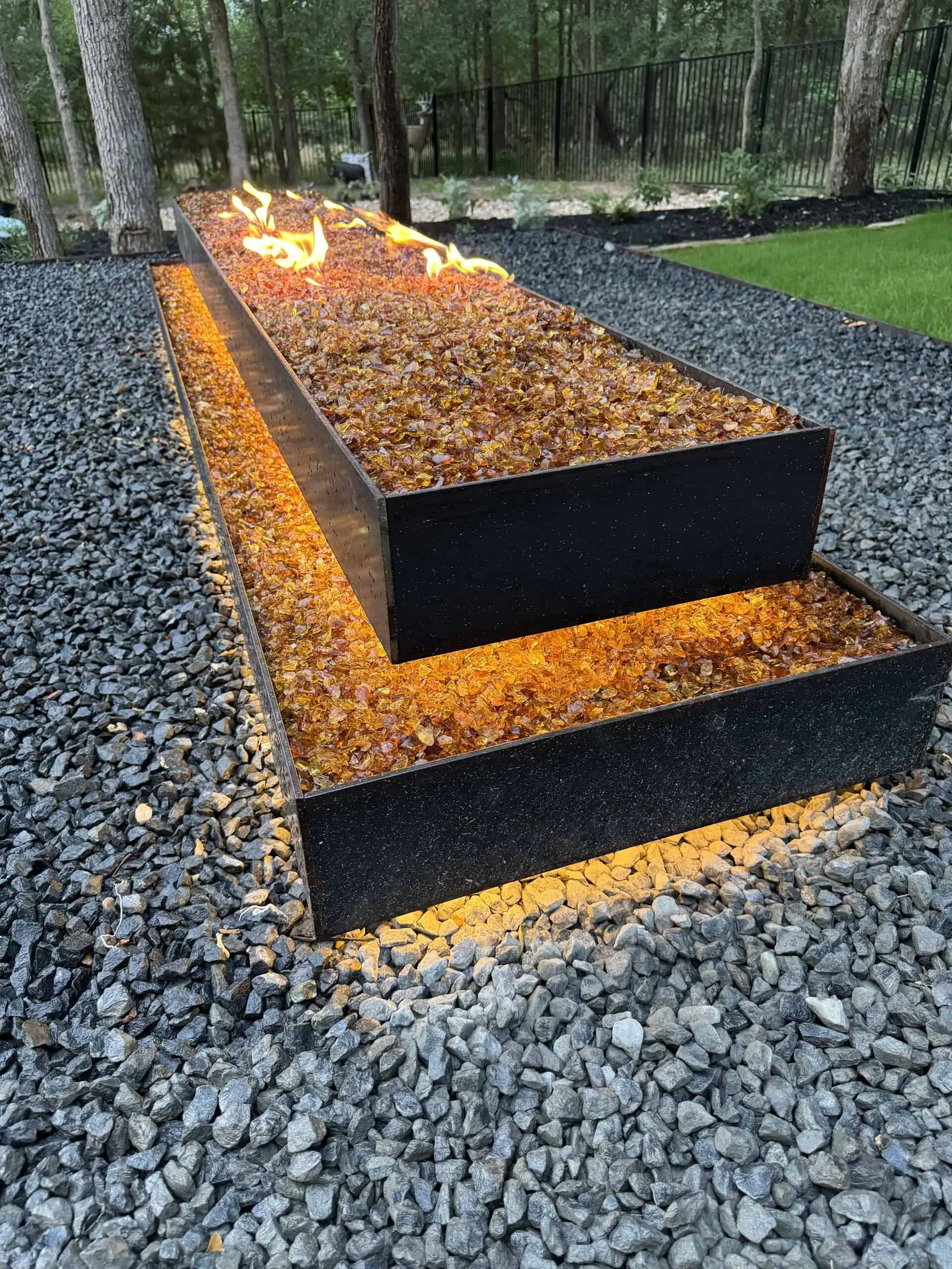 Custom welded steel fire pit with amber fire glass and LED glow — Austin TX