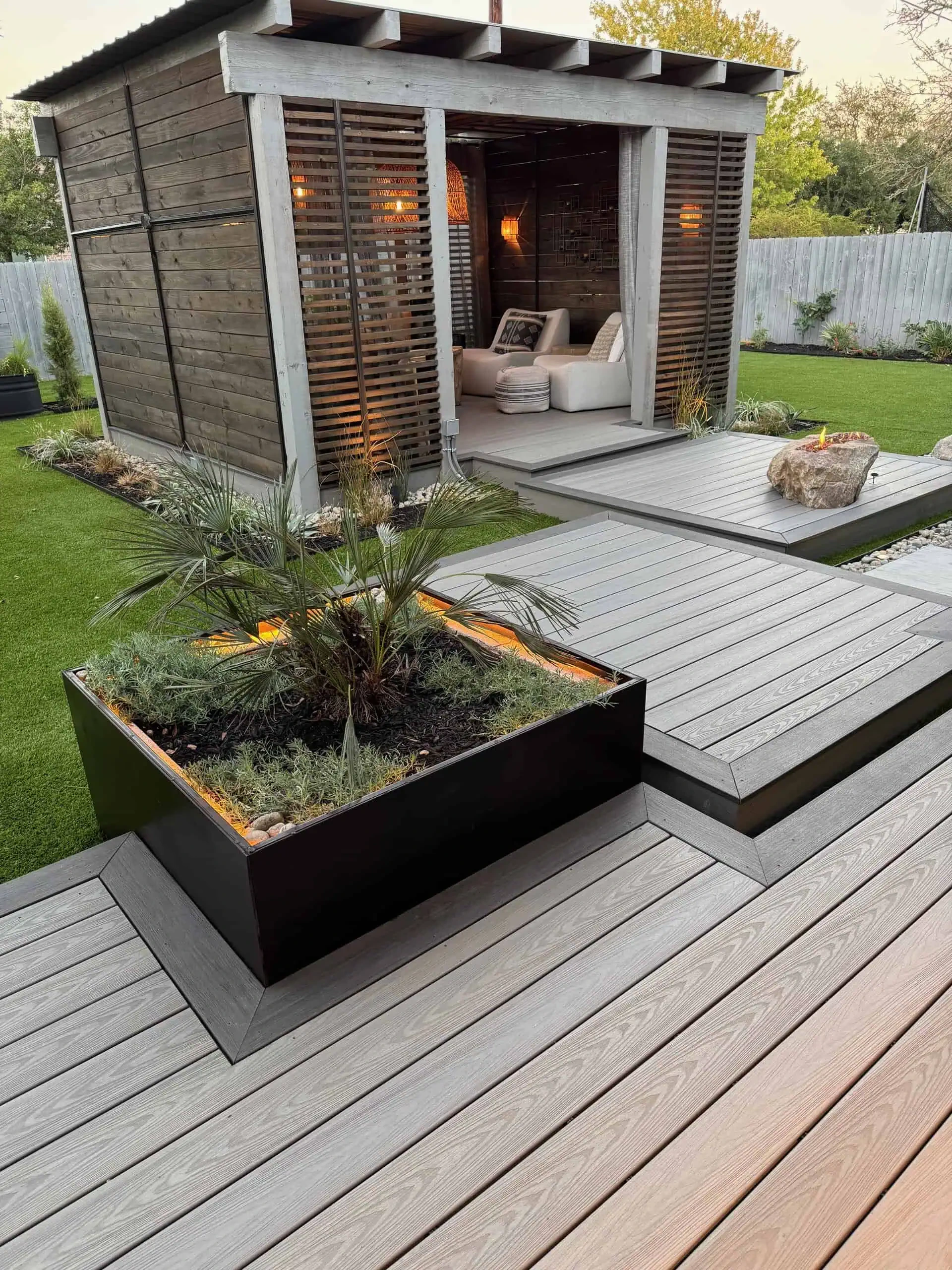 Custom boulder fire pit step set into Sea Salt composite deck — Circle C, Austin TX