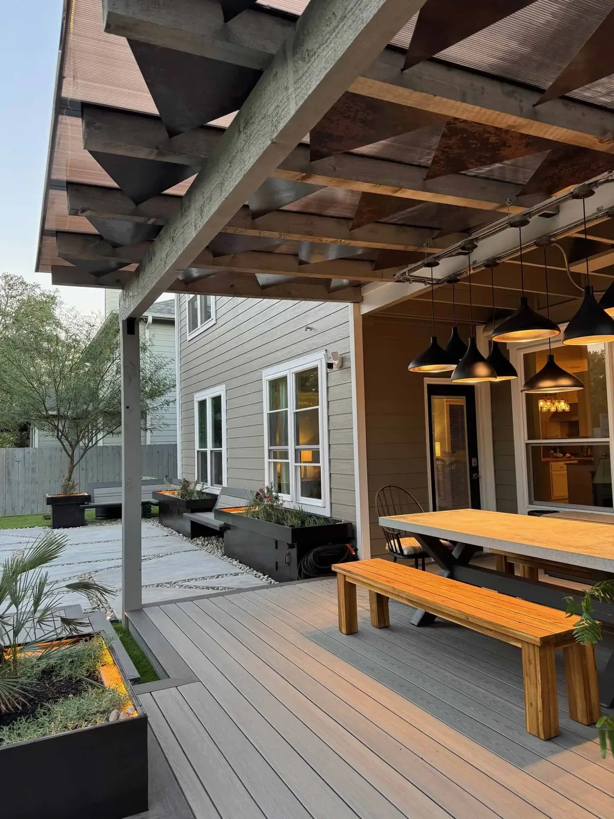 CNC-cut mild steel pergola with geometric shadow panels casting patterned shade on a Circle C deck