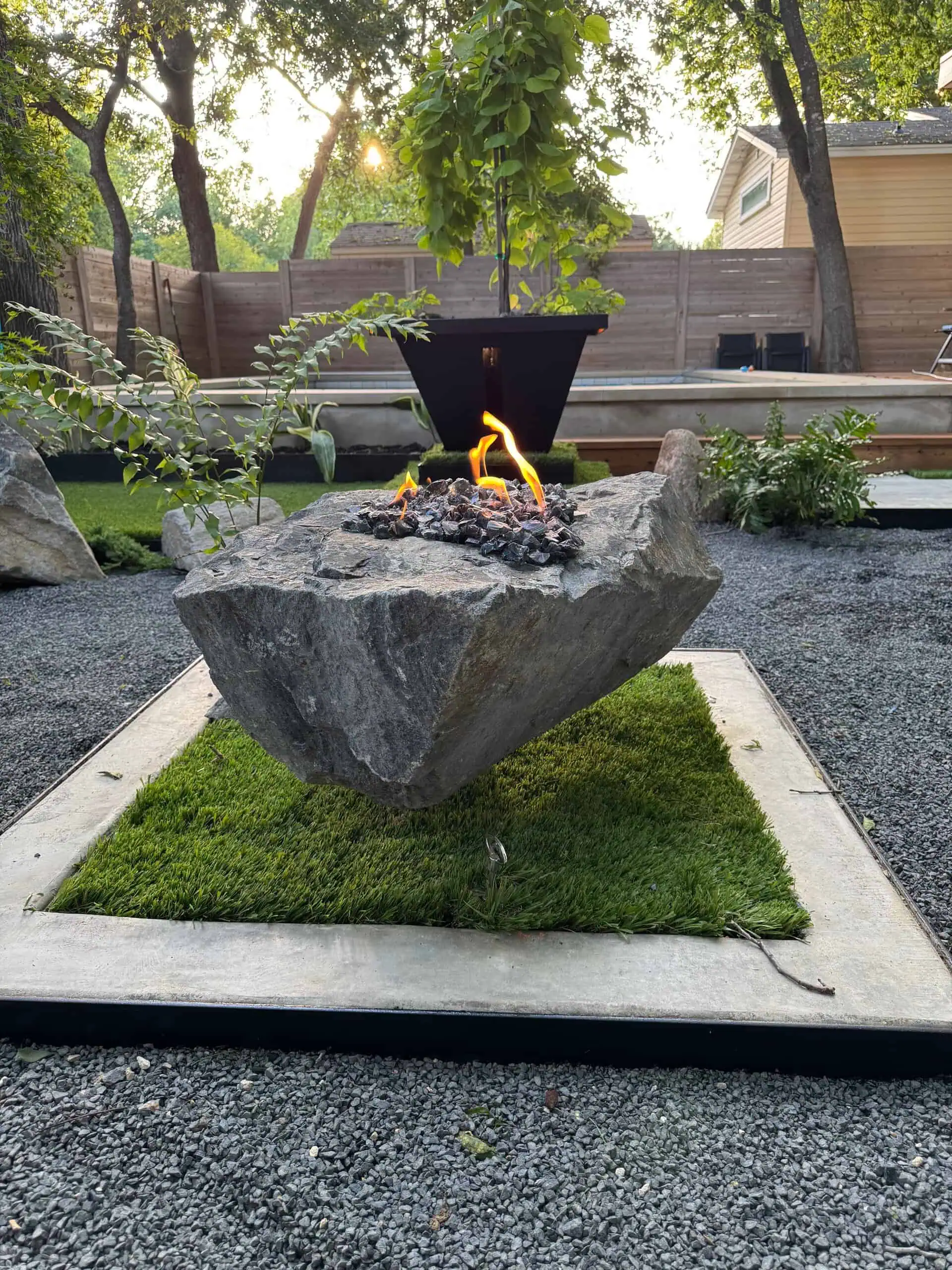 Boulder fire pit with gas burner at golden hour — Austin TX