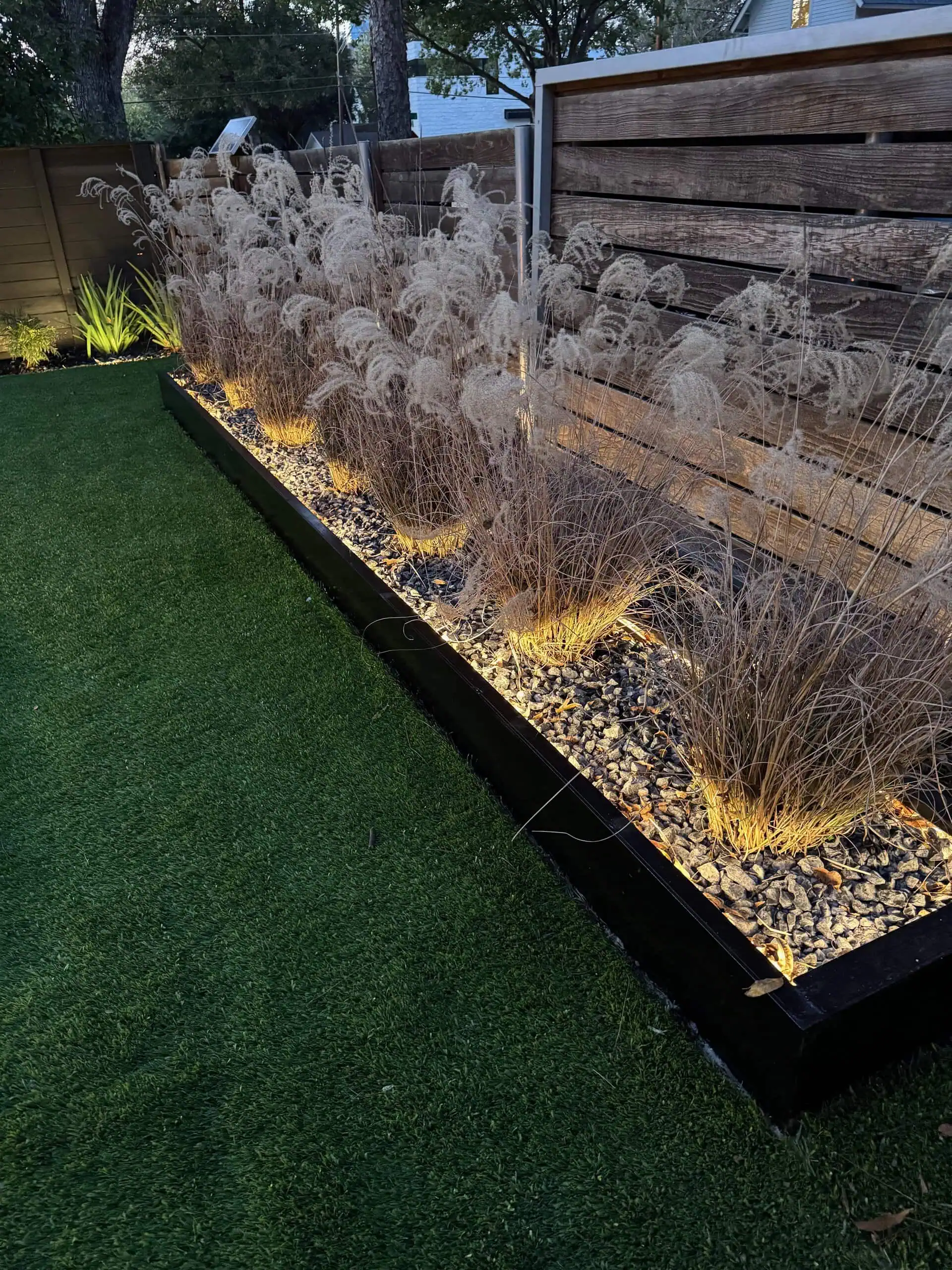 Maiden grass planting bed with low-voltage COB lighting and steel edging — Austin TX